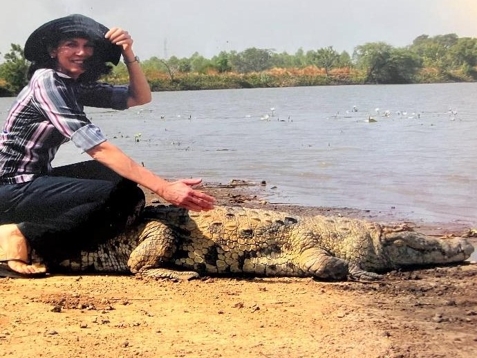 Joyce Kruse sitting on a crocodile on a riverbank